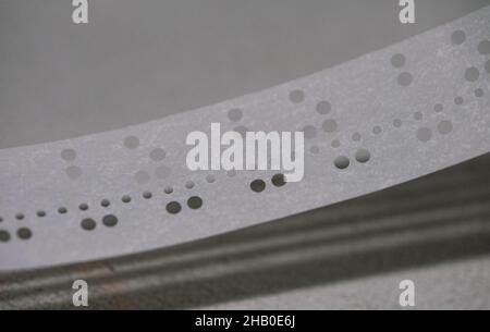 Spool of punched paper tape used for programming early computers. Stock Photo