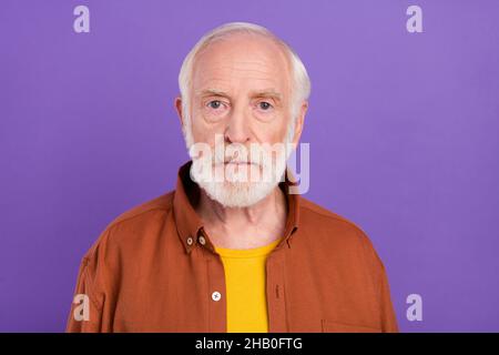 Photo of serious elder man wearing brown shirt isolated over vivid violet color background Stock Photo
