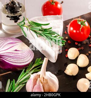 Tomatoes with mozzarella , basil and rosemary. Assorted cheeses on wooden board. Stock Photo