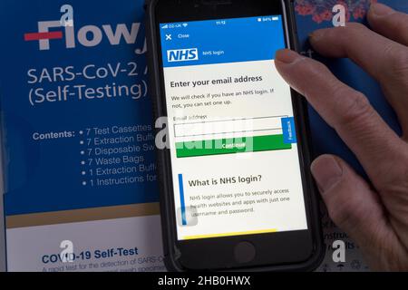 Man open the NHS app's login screen to enter the email address to login to report the Lateral flow test result Stock Photo