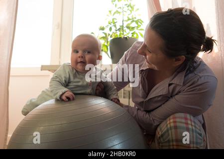 Mother and her baby girl having fun with gymnastic ball. Stock Photo