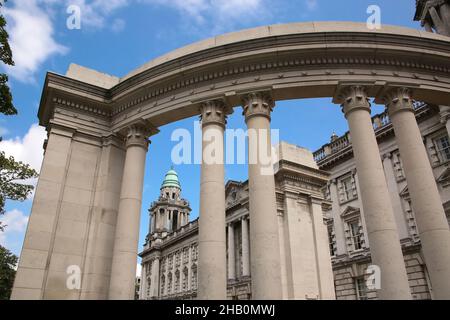 Belfast City Hall building with a classical Renaissance stone exterior and corner tower with columns.  Semi circular monument with columns in front. Stock Photo