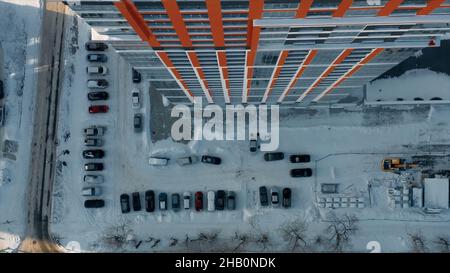 Aerial top view of the typical residential area with many cars parked by the high rise building. Video. Details of a residential house and a snow cove Stock Photo