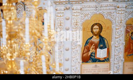 Christian orthodox church interior in white and golden colors. Video. Chandelier with artificial candles in the temple with iconostasis Stock Photo