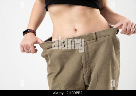 Diet concept. Beautiful sporty woman showing how much weight she lost wearing old big jeans. Healthy lifestyles concept. Stock Photo