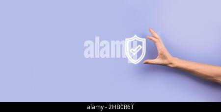Male hand holding protect shield with a check mark icon on blue background. Protection network security computer and safe your data concept Stock Photo