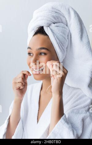 cheerful young african american woman in bathrobe flossing teeth in bathroom Stock Photo