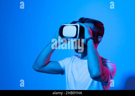 Portraite of young man gamer using virtual reality headset and playing favourite video games with a friends in metaverse. VR, future, gadgets Stock Photo