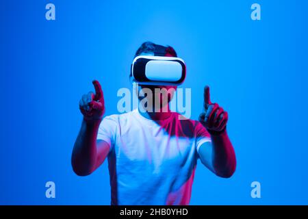 Man in virtual reality glasses. Guy wearing VR headset working in digital simulation, entertains in cyberspace. Stock Photo
