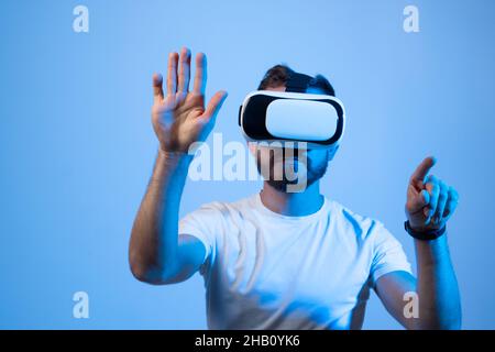 Young bearded man with VR glasses playing a video games in virtual reality. Stock Photo