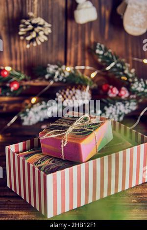 Bright multicolored handmade soap in a gift box on the background of a New Year's decor. Stock Photo