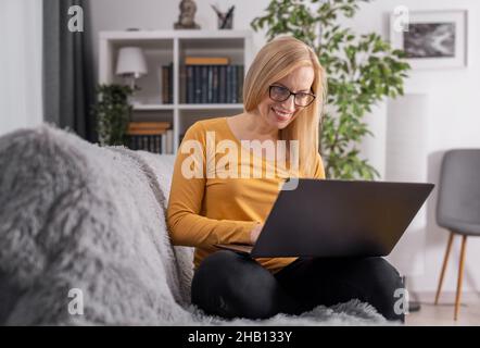 Woman sitting on sofa with laptop Stock Photo