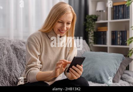 Woman using cell phone at home Stock Photo