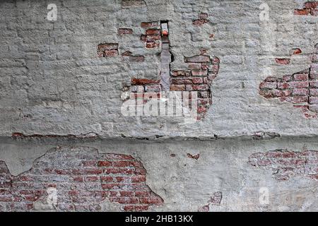 old brick wall with peeling white paint and small window Stock Photo