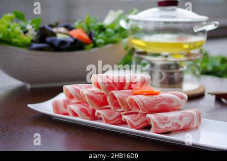 Sliced lamb meat rolls for hotpot on white plate closeup view Stock Photo