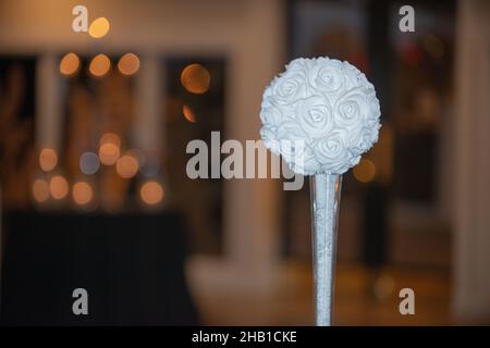 Artificail white flower ball with small diamonds in glass vase table decore with warm bokeh background Stock Photo