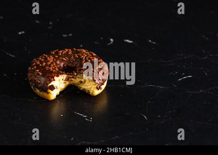 Glazed donut with sprinkles isolated on a black surface Stock Photo