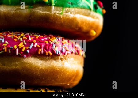 Glazed donuts with sprinkles isolated on a black surface Stock Photo