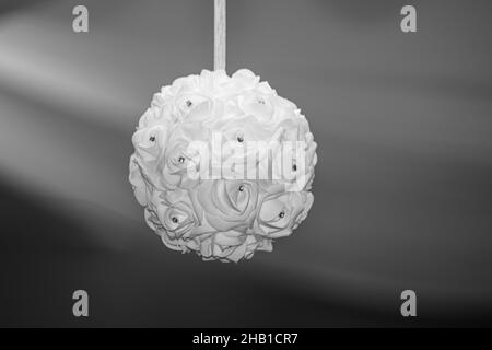 Artificail white flower ball with small diamonds in glass vase table decore with warm blue bokeh background Stock Photo