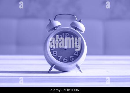 Close up clock for decoration at 8 o'clock stands on a wooden texture with copy space. Very peri toned image. Copy space Stock Photo