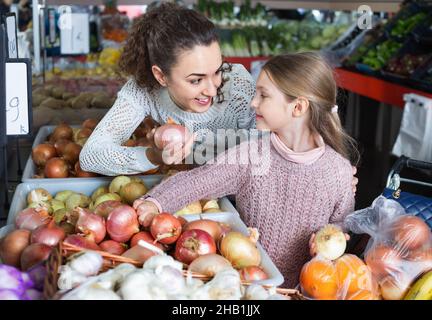 Portrait of mother and smiling little girl purchasing veggies Stock Photo