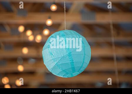 Blue round paper lantern hanging from wood beam ceiling with bokeh Stock Photo