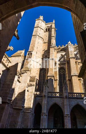 The bell tower of the Cathédrale Saint-Just-et-Saint-Pasteur in Narbonne, Aude department, France, rises behind gargoyles of the cloister; construction began in 1272 but was left unfinished after the plague and a years-long legal dispute between the city and the cathedral chapter, so that only the 41-metre-high choir was completed. Stock Photo