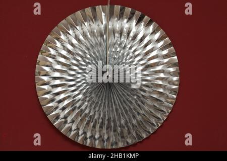 Metallic paper rosette decoration on a red wall Stock Photo