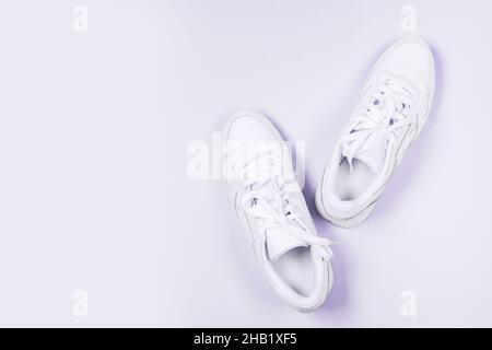 White cream sneakers on isolated pastel background, casual shoes, fashion, footwear, shoe concept, retro. Very peri color toning Stock Photo