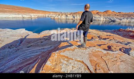 A man hiking near the rocky shoreline of Lake Powell in an area called the Chains in the Glen Canyon Recreation Area of Page Arizona. Stock Photo