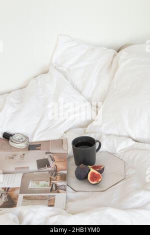 Figs, perfume, coffee on marble table on bed Stock Photo