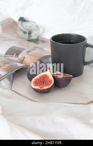 Figs, perfume, coffee on marble table on bed Stock Photo