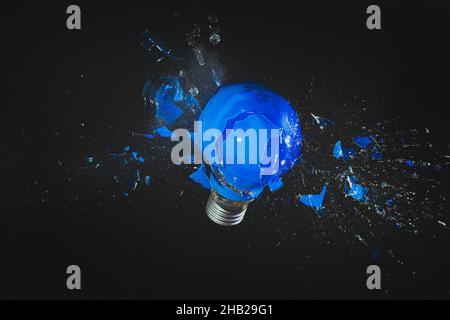 blue light bulb exploding on black. fragility concept. Stock Photo