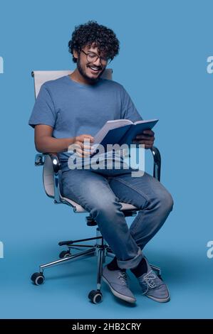 Joyous Indian male focused on his reading Stock Photo