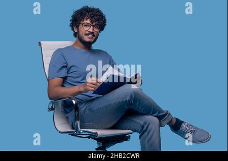 Pleased cute guy with a diary looking ahead Stock Photo