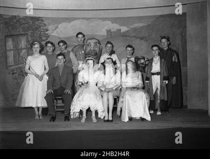 1956, historical, on a wooden stage the cast of Jack and the Beanstalk in their costumes, gather for a group photo, England, UK. First published in 1734 as 'The Story of Jack Spriggins and the Enchanted Bean' - although as a tale dating back many centuries before this -  it is popular English folk story  about a boy who sells the family cow for magic beans, which grows into an enormous beanstalk, which Jack climbs where upon he meets an unfriendly giant or orge. In the '50s, before mass television, amateur dramatics was a popular leisure activiity for people to take part in. Stock Photo
