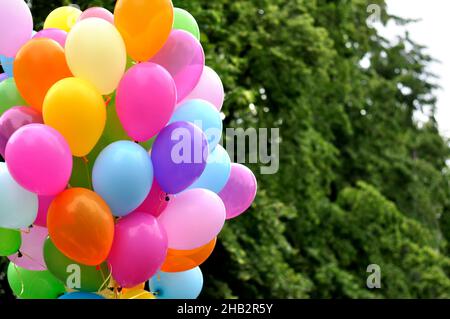 bunch of multicolored balloons in the city festival against trees background Stock Photo