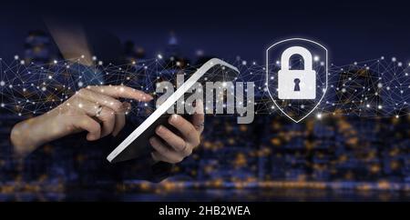 Cyber security, digital crime concept. Hand touch white tablet with digital hologram lock, padlock sign on city dark blurred background. Data protecti Stock Photo