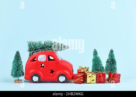 Red car transporting christmas tree snowballs and gift boxes on blue background with Stock Photo