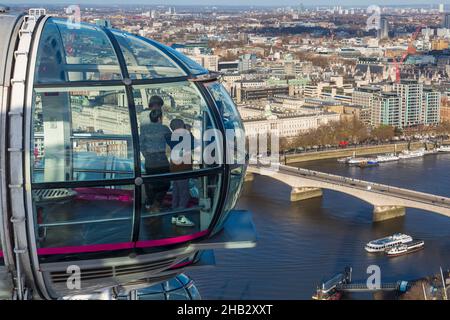 Visitors enjoying the view from London Eye pod looking North East at Southbank, London UK in December - Waterloo Bridge over River Thames Stock Photo