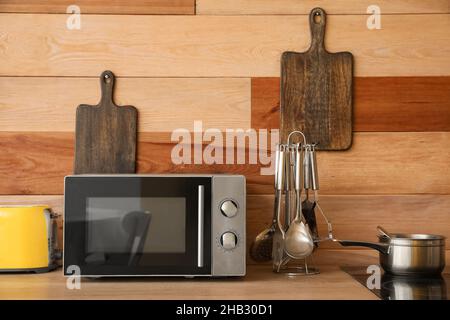 Microwave oven on wooden tabletop in kitchen Stock Photo