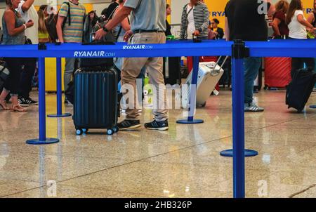 Palma, Spain - September 25, 2019: Passengers with their luggage waiting in airport hall, closeup detail on their feet and legs, blue boundary separat Stock Photo