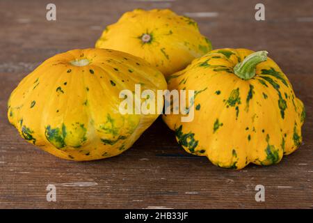 three patty pan squashes on wooden table, harvest of fresh vegetables, side view Stock Photo