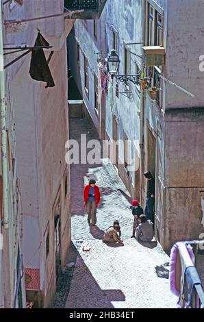 Children playing on street in narrow alleyway in old housing area of Lisbon, Portugal, 1975 Stock Photo