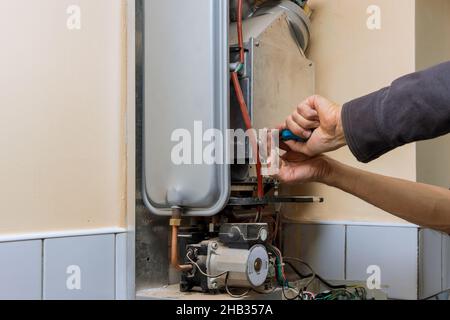 Repairman fixing a gas water heater with repair service Stock Photo