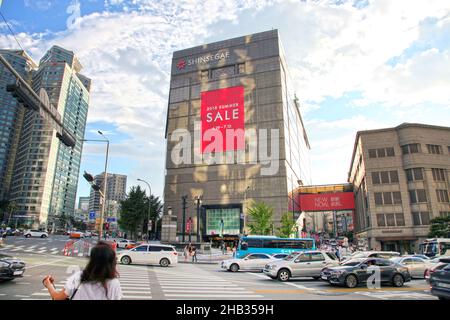 Shinsegae main department store in Myeong-dong with an intersection with pedestrian crossing and cars in the street. Stock Photo