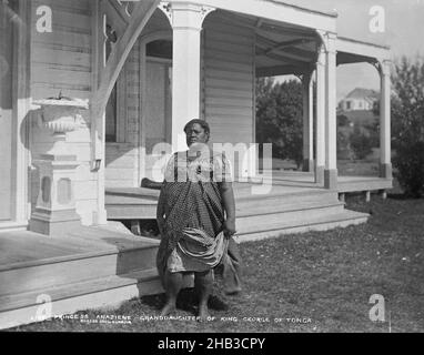 Princess Anaziene, Granddaughter of King George of Tonga, Burton Brothers studio, photography studio, 29 July 1884, New Zealand, black-and-white photography, Tongan woman standing at bottom of step in front of colonial wooden building with large verandah. Woman is holding dress in left hand. A large ornate vase is on a pedestal on verandah. Another building is visible through verandah (right) on top of a rise Stock Photo