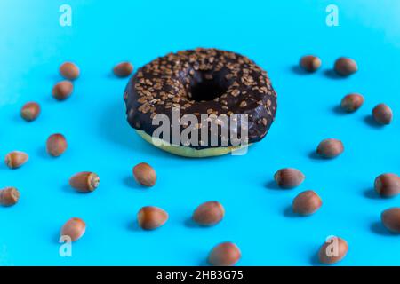 Donut with hazelnuts on a blue background, close up Stock Photo