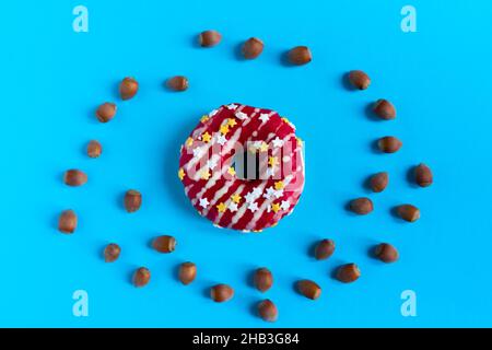 Donut with hazelnuts on a blue background, close up Stock Photo