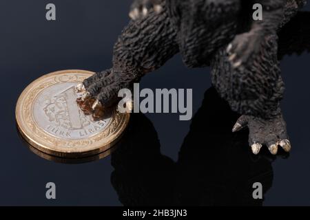Monster feet standing on one Turkish Lira coin. TL losing value against inflation. Financial and economy dark background with copy space. Stock Photo